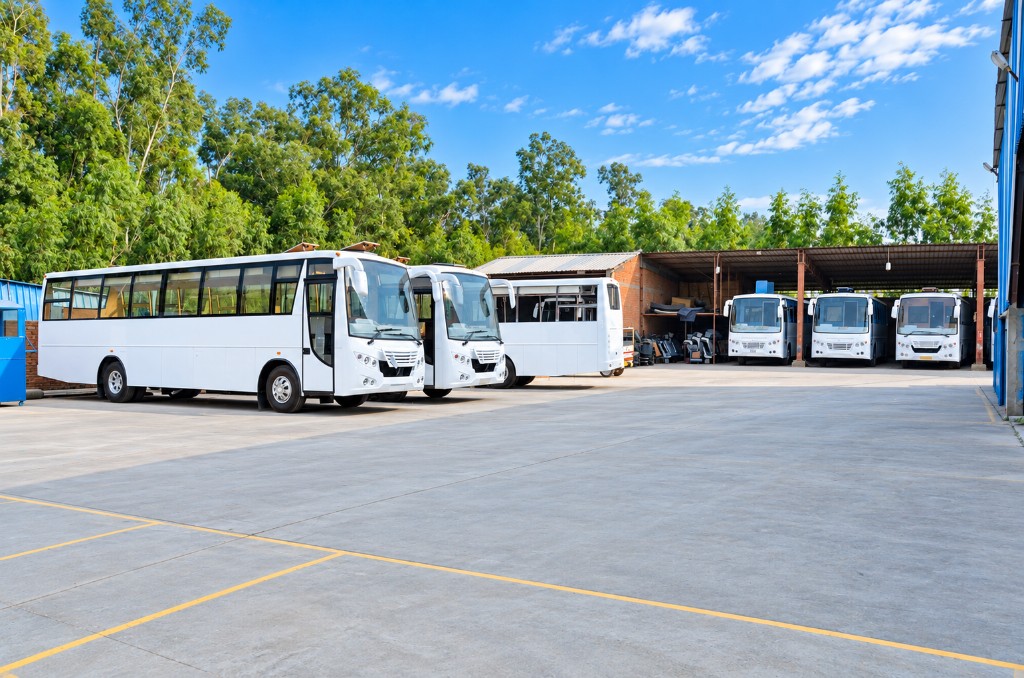Finished bus bodies parked in the Unitech Motors yard with more under the covered bays
